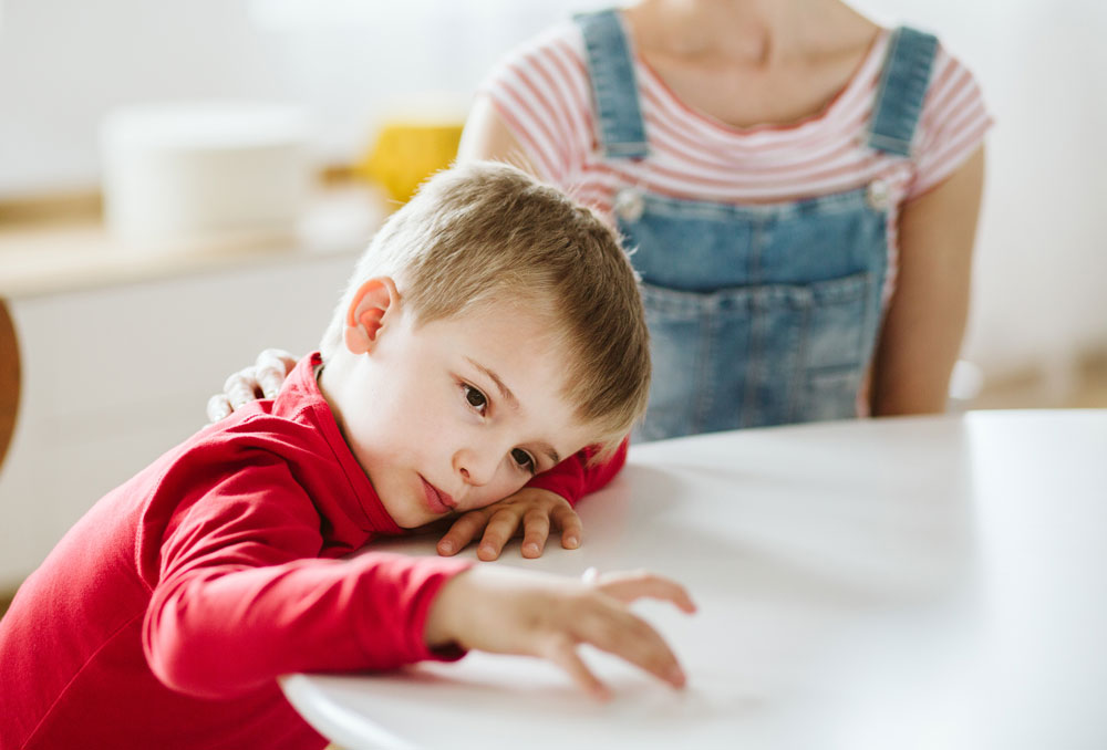 person providing comfort to a child who appears to be resting their head on a surface
